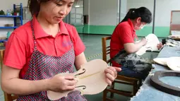 Para pekerja membuat biola di sebuah bengkel kerja di Queshan, Provinsi Henan, China, Rabu (20/5/2020). Kawasan industri penghasil alat musik tersebut mampu memproduksi 30.000 biola dan selo setiap tahun. (Xinhua/Zhu Xiang)