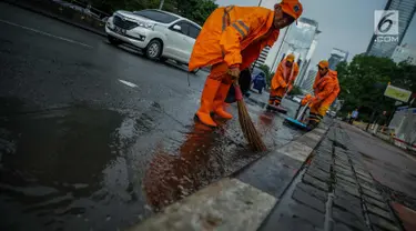 Petugas Dinas Kebersihan membersihkan genangan air usai hujan di kawasan jalan Sudirman, Jakarta, Rabu (22/11). Buruknya sistem drainase membuat petugas membersihkan genangan setiap kali hujan, meski dengan peralatan seadanya. (Liputan6.com/Faizal Fanani)