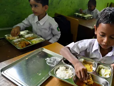 Beberapa siswa menikmati makanan yang disediakan lewat program pemerintah Indonesia, Makan Bergizi Gratis (MBG), di sebuah sekolah dasar di Darul Kamal, Provinsi Aceh pada Senin 13 Oktober 2025. (CHAIDEER MAHYUDDIN/AFP)