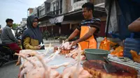 Pedagang memotong daging ayam saat melayani pembeli di sebuah pasar tradisional usai gempa dan tsunami melanda Palu, Sulawesi Tengah, Kamis (4/10). Pedagang mengaku memperdagangkan barangnya dengan harga standar. (Permata SAMAD/AFP)