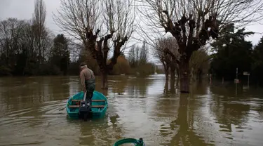 Marcel Leclercq menggunakan perahu di jalan yang banjir di pulau Vaux, sebelah barat Paris, (30/1). Sungai Seine yang meluap akibat hujan deras dalam 50 tahun telah menelan dermaga di Paris, Prancis. (AP Photo / Thibault Camus)