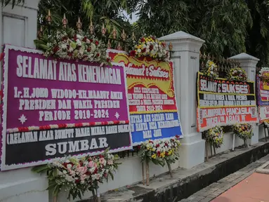 Pejalan kaki melintasi karangan bunga bertuliskan ucapan selamat untuk Joko Widodo (Jokowi) dan Ma'ruf Amin di gedung Sekretariat Negara, Jakarta, Senin (22/4). Karangan bunga dari pendukung Jokowi-Ma'ruf tersebut ditujukan atas kemenangan pasangan itu pada Pilpres 2019. (Liputan6.com/Faizal Fanani)