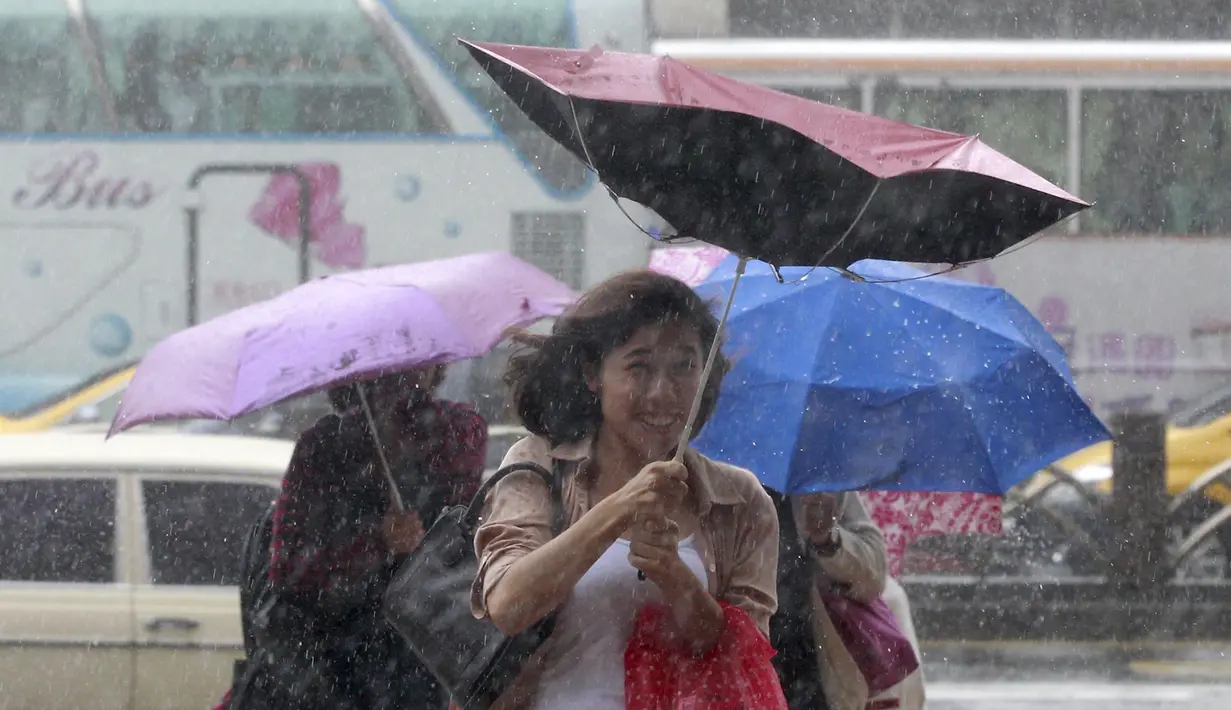 Warga memegang payung sambil berjalan menghindari angin kencang yang disebabkan topan Dujuan di Taipei, Taiwan, Senin (28/9). Ribuan orang diungsikan untuk menghadapi topan raksasa Dujuan yang diprediksikan akan menyerang Taiwan. (REUTERS/Pichi Chuang)