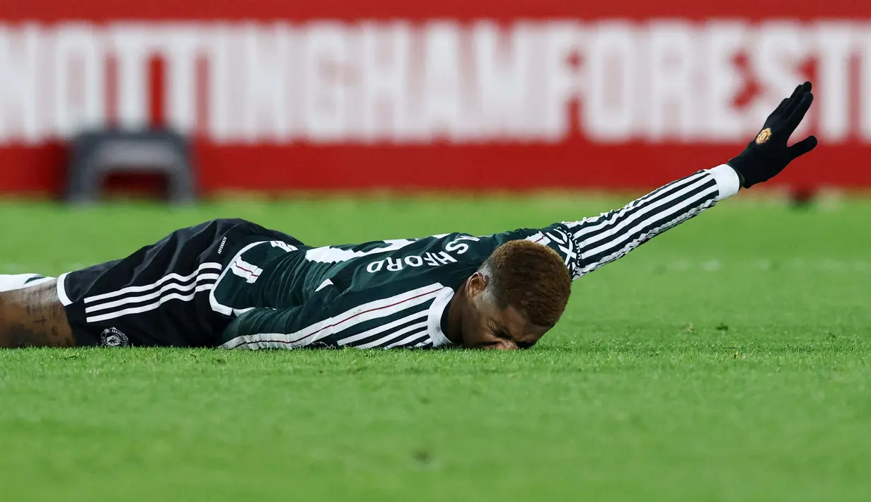 Pemain Manchester United, Marcus Rashford, terkapar saat melawan Nottingham Forest pada laga pekan ke-20 Premier League 2023/2024, Minggu (31/12/2023) dini hari WIB. MU takluk dengan skor 1-2. (AFP/Darren Staples)