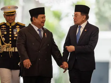 Presiden Republik Indonesia Prabowo Subianto (tengah) dan Perdana Menteri Malaysia Anwar Ibrahim (kanan) berjalan bersama menjelang pertemuan bilateral di Istana Kepresidenan, Jakarta pada 29 Juli 2025. (Yasuyoshi CHIBA/AFP)