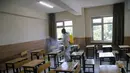 Seorang staf mendisinfeksi ruang kelas yang akan digunakan untuk ujian masuk universitas di Ankara, Turki (26/6/2020). (Xinhua/Mustafa Kaya)