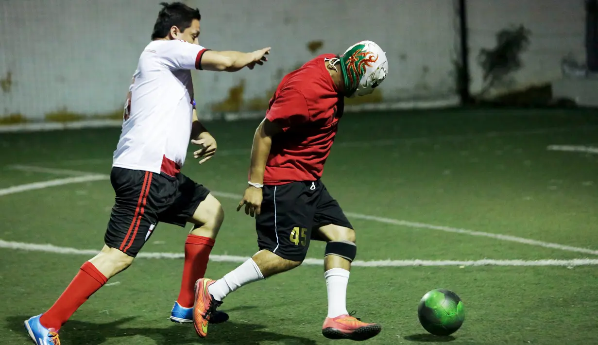 Seorang Pegulat berusaha melewati lawannya saat bermain futsal di Monterrey, Meksiko (29/2). Sejumlah pegulat profesional Meksiko mencoba hal baru bermain futsal untuk melatih kebugaran pegulat. (REUTERS/Daniel Becerril)