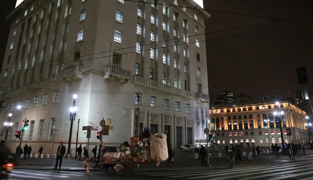 Seorang wanita tunawisma membawa gerobaknya yang dipenuhi barang daur ulang pada malam dengan cuaca dingin di pusat kota Sao Paulo, 19 Juli 2017. Menurut pejabat setempat, setidaknya 16.000 tunawisma tinggal di kota Sao Paulo. (AP Photo / Andre Penner)