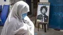 Warga melintas di depan poster Jimi Hendrix kota pesisir Maroko Essaouira pada 10 September 2020. Kisah tentang petualangan Hendrix di Maroko ada beragam versi; dia melintasi negara dengan van, mencoba membeli sebuah pulau di lepas pantai Essaouira dan seluruh desa Diabat. (AFP/Fadel Senna)