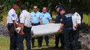Polisi mengangkat puing pesawat yang diduga milik MH370 untuk diamankan di pantai Saint - Andre, Perancis, Rabu (29/30/2015). Puing tersebut ditemukan oleh orang-orang yang sedang membersihkan pantai. (REUTERS/Prisca Bigot)