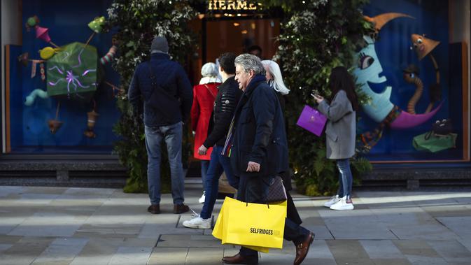 Orang-orang berjalan melewati toko sambil membawa tas belanja di Mayfair setelah pelonggaran pembatasan virus corona COVID-19 menyusul berakhirnya kebijakan penguncian nasional atau lockdown kedua di Inggris, di London, Sabtu (5/12/2020). (AP Photo/Alberto Pezzali)