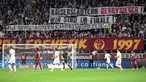 Suporter FC Metz membentangkan spanduk bertulisakan "Pemenang derby Kaiserlautern, kami berada di final" untuk mendukung FC Kaiserlautern yang mencapai final Piala DFB Pokal pada laga lanjutan Liga Prancis 2023/2024 melawan RC Lens di Saint-Symphorien Stadium, Longeville-les-Metz, Prancis, Sabtu (13/04/2024) dini hari WIB. (AFP/Jean-Christophe Verhaegen)