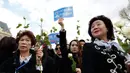 Sejumlah wanita membawa mawar putih dan spanduk saat menggelar demo di Place de la Republique, di Paris, Prancis (2/4). (AFP/Benjamin Cremel)