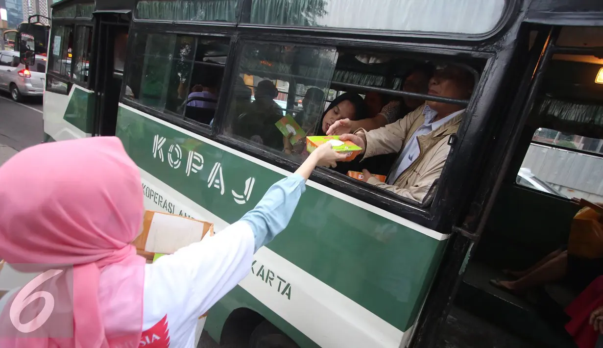 Penumpang bus mengambil takjil gratis yang dibagikan oleh Karyawan Asia Pulp & Paper (APP) Sinar Mas di kawasan Bundaran HI, Jakarta (24/6). (Liputan6.com/ Immanuel Antonius)