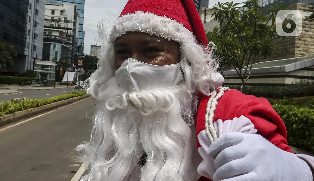 Pria berkostum Sinterklas mengenakan masker saat membagikan kopi gratis kepada warga di kawasan Jalan Jenderal Sudirman, Jakarta, Sabtu (19/12/2020). Selain menyambut Natal, pembagian kopi tersebut juga untuk mempromosikan produk unggulan para petani di Indonesia. (Liputan6.com/Johan Tallo)