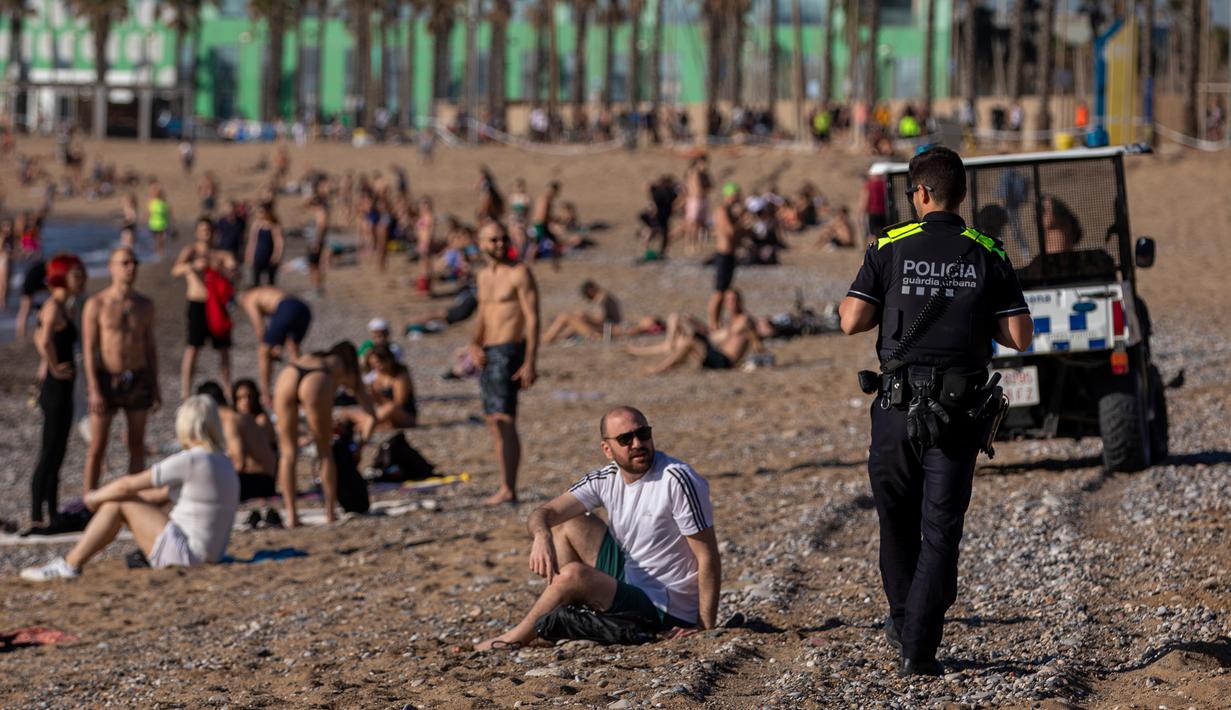 Petugas polisi meminta orang-orang untuk tidak duduk sambil berpatroli di pantai di Barcelona, Spanyol, Rabu, (20/5/2020). Barcelona mengizinkan orang untuk berjalan di pantai untuk pertama kalinya sejak dimulainya penguncian virus coronavirus lebih dari dua bulan lalu. (AP Photo/Emilio Morenatti)