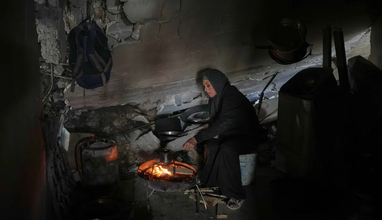 Di penghujung tahun 2025, krisis hunian bagi warga Palestina tetap berada pada tingkat yang sangat kritis akibat konflik yang berkepanjangan antara Israel dan Milisi Hamas di Jalur Gaza. Tampak dalam foto, Amani Halawa menghangatkan minuman di atas api di sebuah ruangan reyot, bertahan hidup di tengah reruntuhan rumahnya yang rusak di Jabaliya, Kota Gaza, Selasa, 25 November 2025. (AP Photo/Jehad Alshrafi)