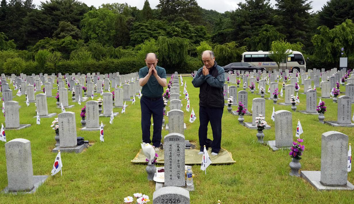 Warga Korea Selatan Choe Geun-ho dan Choe In-suck (kiri) berdoa di depan nisan paman mereka Choe Hyun-jun yang gugur saat Perang Korea pada peringatan Hari Pahlawan di Pemakaman Nasional Seoul, Seoul, Korea Selatan, Senin (6/6/2022). (AP Photo /Ahn Young-joon)