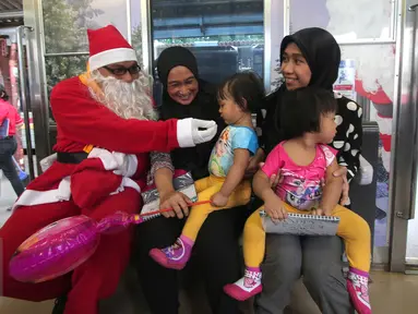 Sinterklas bercengkrama dengan para penumpang KRL di Jakarta, Jumat (25/12/2015). Keberadaan Sinterklas ini merupakan bentuk pelayanan KCJ dalam memperingati hari Natal. (Liputan6.com/Angga Yuniar)