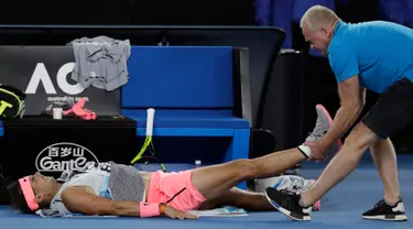 Petenis Spanyol, Rafael Nadal mendapat perawatan dari pelatihnya terkait cedera paha kanan pada perempat final Australia Terbuka 2018 di Melbourne, Selasa (23/1). Nadal mundur di set kelima saat menghadapi petenis Kroasia, Marin Cilic. (AP/Dita Alangkara)