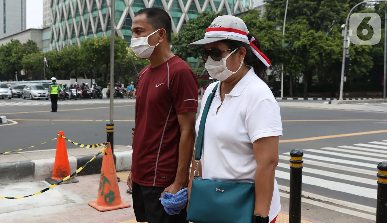 Warga berdiri sikap sempurna di perempatan Bank Indonesia jalan MH Thamrin, Jakarta, Senin (17/8/2020). Dalam rangka HUT ke-75 tahun Kemerdekaan Indonesia, masyarakat menghentikan aktivitas selama tiga menit sebagai bentuk penghormatan detik-detik proklamasi. (Liputan6.com/Helmi Fithriansyah)