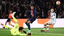 Pemain PSG, Kylian Mbappe (tengah) berusaha melepaskan tembakan meski ditepis oleh kiper Real Sociedad, Alex Remiro pada laga leg pertama 16 besar Liga Champions 2023/2024 di Parc des Princes, Paris, Prancis, Kamis (15/02/2024) WIB. (AFP/Franck Fife)