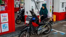 Seorang pengendara sepeda motor mengisi bahan bakar motornya di sebuah Stasiun Pengisian Bahan Bakar Umum (SPBU) yang dioperasikan oleh Pertamina, perusahaan minyak dan gas milik negara Indonesia, di Yogyakarta, pada Sabtu 28 Maret 2026. Konflik antara Iran dengan Amerika Serikat–Israel serta pembatasan di jalur strategis Selat Hormuz berdampak pada lonjakan harga minyak global. (DEVI RAHMAN/AFP)
