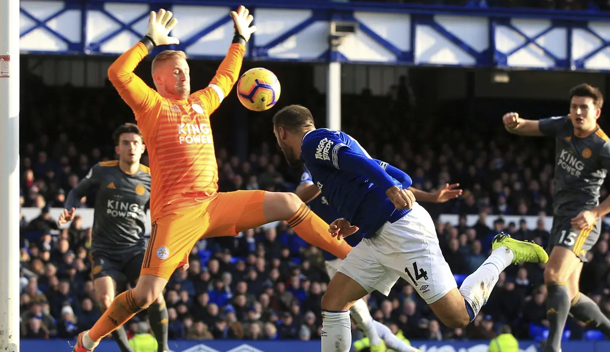 Kiper Leicester City, Kasper Schmeichel, menghadang sundulan pemain Everton, Cenk Tosun, pada laga Premier League di Stadion Goodison Park, Selasa (1/1). Leicester City menang 1-0 atas Everton. (AP/Peter Byrne)