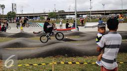Seorang ayah yang menggendong anak menonton aksi pesepeda BMX Taman Kalijodo, Jakarta, Minggu (15/01). Sejak skate park dan lintasan sepeda BMX dibuka untuk umum, taman tersebut tidak pernah sepi pengunjung. (Liputan6.com/Fery Pradolo)