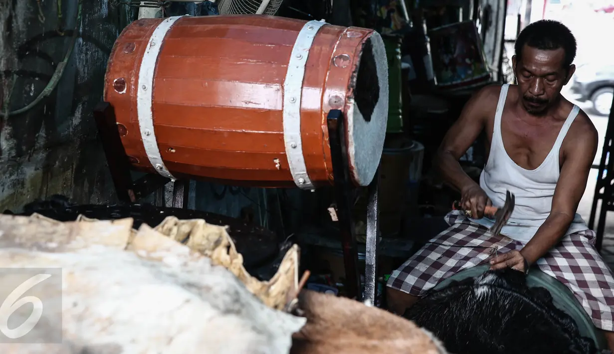 Ridho (52) memasang pengikat untuk membuat bedug di kawasan, Tanah Abang, Jakarta, (17/6). Menjelang lebaran, sejumlah pedagang menjual aneka ragam bedug yang dijual dari harga Rp. 100 ribu hingga Rp 4 juta. (Liputan6.com/Faizal Fanani)