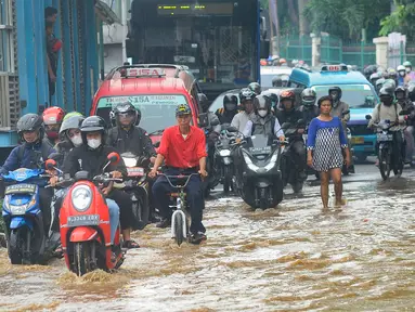 Pengendara menerobos banjir yang meggenang di Jalan Raya Bogor depan Pasar Induk Kramat Jati, Jakarta, Kamis (30/11/2023). Hujan deras serta meluapnya air Kali Baru Timur tersebut menyebabkan akses Jalan Raya Bogor tergenang air setinggi 60 cm sehingga membuat kemacetan lalu lintas. (merdeka.com/Arie Basuki)