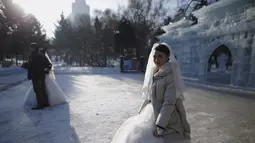 Pengantin baru menunggu giliran untuk berfoto di depan bangunan yang terbuat dari balok es usai upacara pernikahan massal yang merupakan bagian dari Festival Es dan Salju Harbin di provinsi Heilongjiang, China, Rabu (6/1/2016). ( REUTERS/ Aly Song)