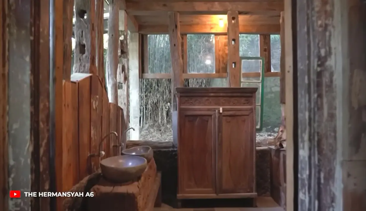 Selain meja kursi model kuno, tampak beberapa lemari juga model kuno. Bangunan dinding hampir semua menggunakan kayu kuno hingga jendela model kuno. [Youtube/The Hermansyah A6]