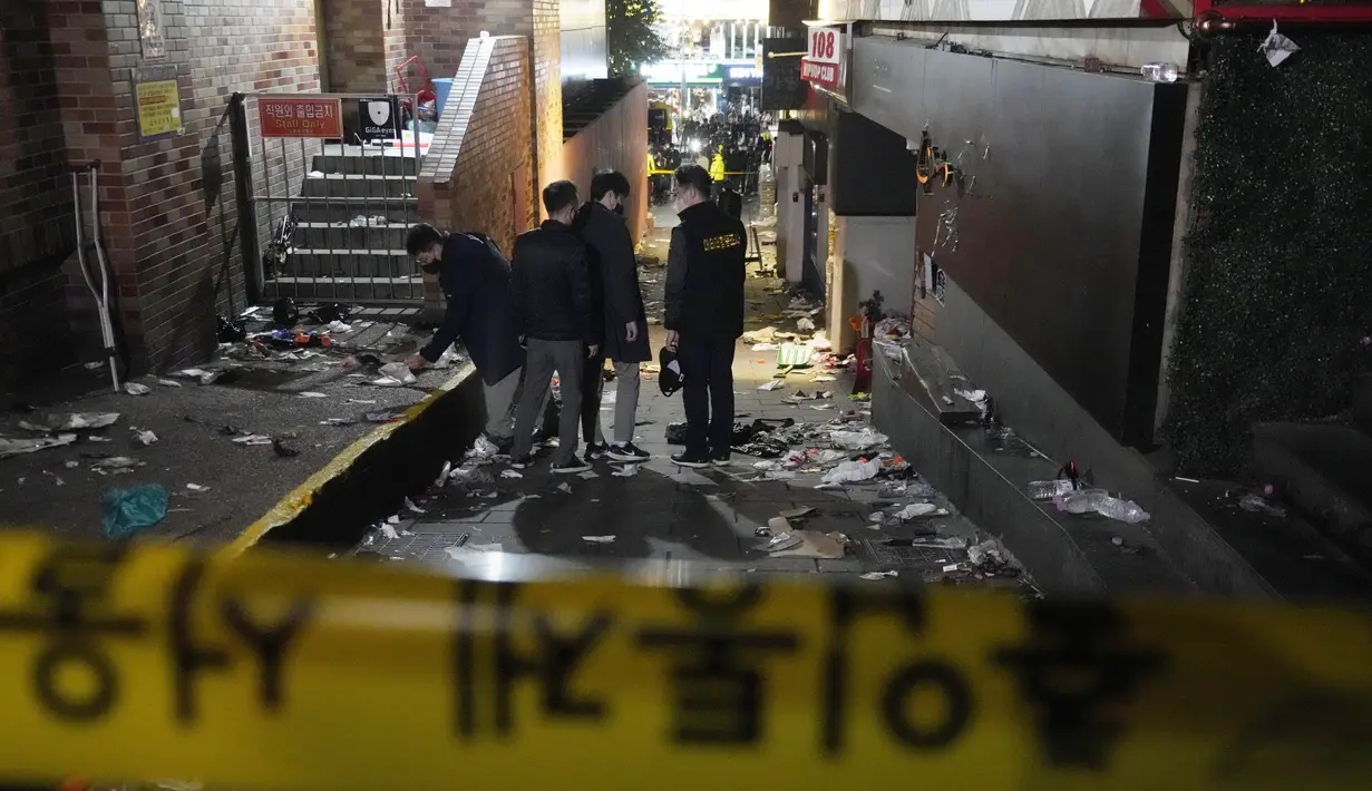Petugas kepolisian memeriksa lokasi korban tewas dan luka-luka dalam tragedi Halloween Itaewon di Seoul, Korea Selatan, Minggu (30/10/2022). Rekaman media sosial menunjukkan ratusan orang yang memadati gang sempit dan miring itu terjebak dan tidak bisa bergerak ketika petugas darurat dan polisi berusaha menarik mereka untuk bebas. (AP Photo/Ahn Young-joon)
