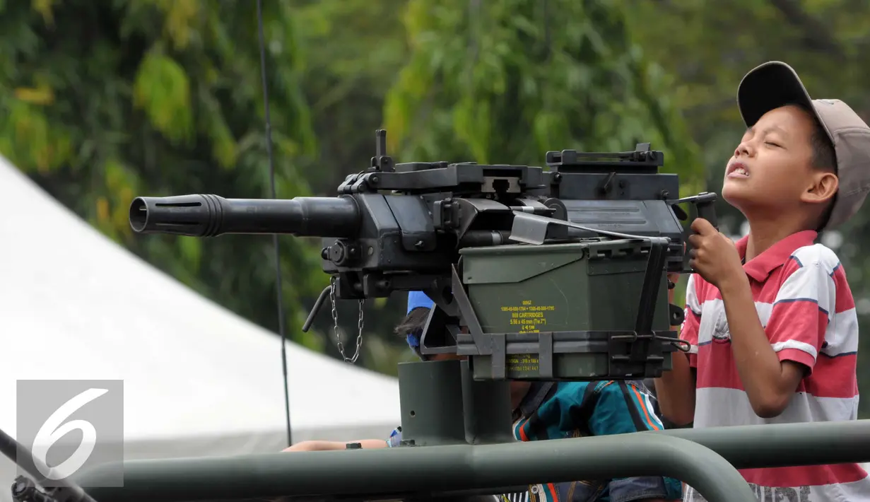 Seorang anak mencoba senjata ketika menaiki kendaraan tempur saat HUT Kopassus ke-64, Jakarta, (16/4). HUT mengangkat Tema Loyalitas, Moralitas dan Integritas demi mewujudkan Prajurit Hebat Profesional dan Dicintai Rakyat. (Liputan6.com/Helmi Afandi)