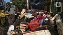Petugas membersihkan sampah sisa banjir di Kebalen, Jakarta, Minggu (21/2/2021). Banjir yang terjadi kemarin karena curah hujan yang tinggi meninggalkan sampah di rumah warga. (Liputan6.com/Johan Tallo)