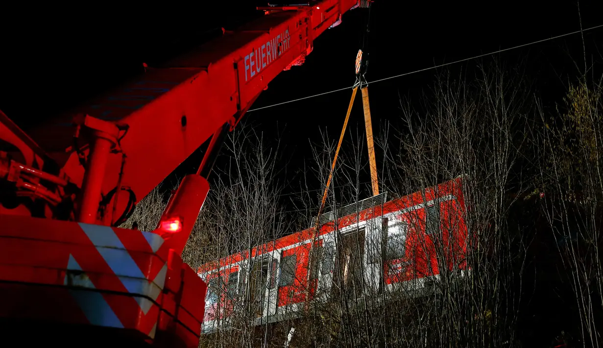 Petugas mengevakuasi rangkaian kereta komuter S-bahn yang tabrakan di Schaeftlarn di distrik Munich, Jerman pada 14 Februari 2022. Bagian depan kereta saling menghantam satu sama lain saat melaju di satu jalur lintasan. (MICHAELA REHLE / AFP)