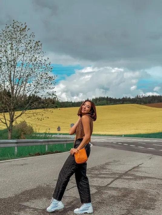 Berpose dengan latar ladang bunga tulip, Gisel tampil stylish dengan knit top, jogger pants, dan sling bag warna oranye cerah. [Foto: IG/gisel_la].