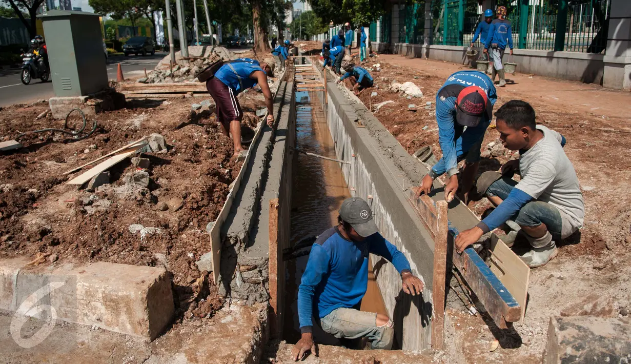 Sejumlah pekerja menyelesaikan pembuatan saluran air di Jalan Asia Afrika, Senayan, Jakarta, Rabu (5/4). Saluran yang sempat tidak berfungsi tersebut di normalisasikan dengan kedalaman 150cm Lebar 100cm dan panjang 195m. (Liputan6.com/Gempur M Surya)