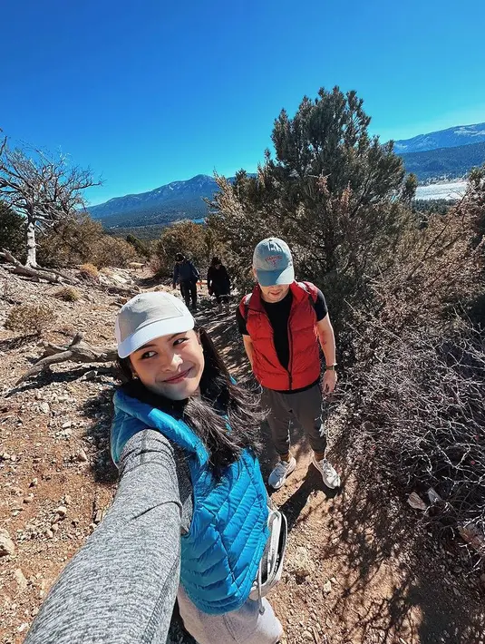 Maudy Ayunda dan sang suami memilih hiking di California, Amerika saat liburan akhir tahun. Keduanya kompak mengenakan padding vest. [@maudyayunda]