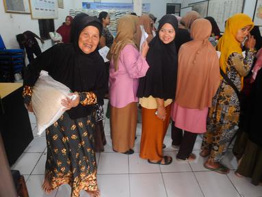 Keluarga penerima manfaat (KPM) membawa bantuan sosial pangan beras saat berlangsung penyaluran di kantor Kelurahan Meruyung, Depok, Sabtu  (11/5/2024). (merdeka.com/Arie Basuki)