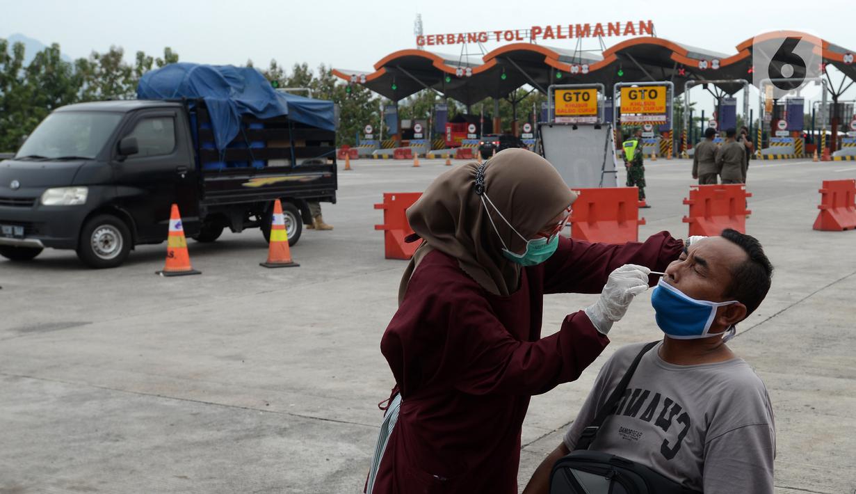 Petugas medis melakukan tes COVID-19 terhadap seorang pria di Gerbang Tol Palimanan, Jakarta, Jumat, (7/5/2021). Gerbang Tol Palimanan sepi karena adanya kebijakan larangan mudik Lebaran pada tanggal 6-17 Mei 2021 untuk memutus penyebaran COVID-19. (merdeka.com/Imam Buhori)
