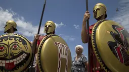 Seorang wanita berdiri di antara Para pria menggunakan pakaian tentara Yunani kuno membawa tombak dan tameng di sekitar Syntagma Square. Athena, Yunani (21/6/2015). (REUTERS/Marko Djurica)