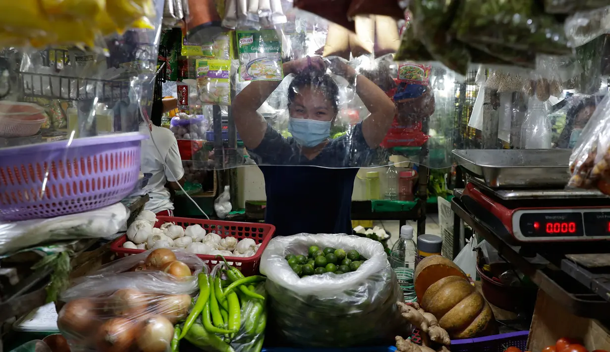 Pedagang menata rambutnya di balik lembaran plastik untuk mencegah virus corona di sebuah pasar di kota Quezon, Filipina, Selasa (22/9/2020). Presiden Filipina Rodrigo Duterte mengatakan telah memperpanjang status masa darurat Covid-19 di negaranya hingga satu tahun ke depan. (AP Photo/Aaron Favila)