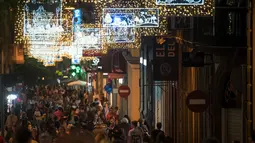 Orang-orang berjalan di bawah lampu Natal yang menghiasi jalan Santa Cruz de Tenerife di pulau Canary Tenerife, Spanyol (19/12). (AFP Photo/Desiree Martin)