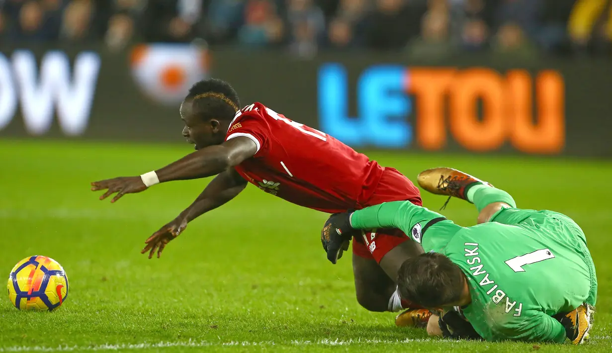 Aksi pemain Liverpool, Sadio Mane (kiri) berebut bola dengan kiper Swansea City, Lukasz Fabianski pada lanjutan Premier League di Liberty Stadium, Swansea, (22/1/2018). Liverpool kalaj dari Swansea 0-1. (AFP/Geoff Caddick)
