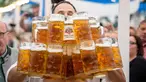 Oliver Struempfel membawa gelas bir sebanyak-banyaknya sambil berjalan untuk memecahkan rekor saat bersaing pada festival tradisional Gillamoos di Abensberg, Jerman, Minggu (3/9). Struempfel berhasil menyusun 29 gelas bir besar. (Matthias Balk/dpa via AP)