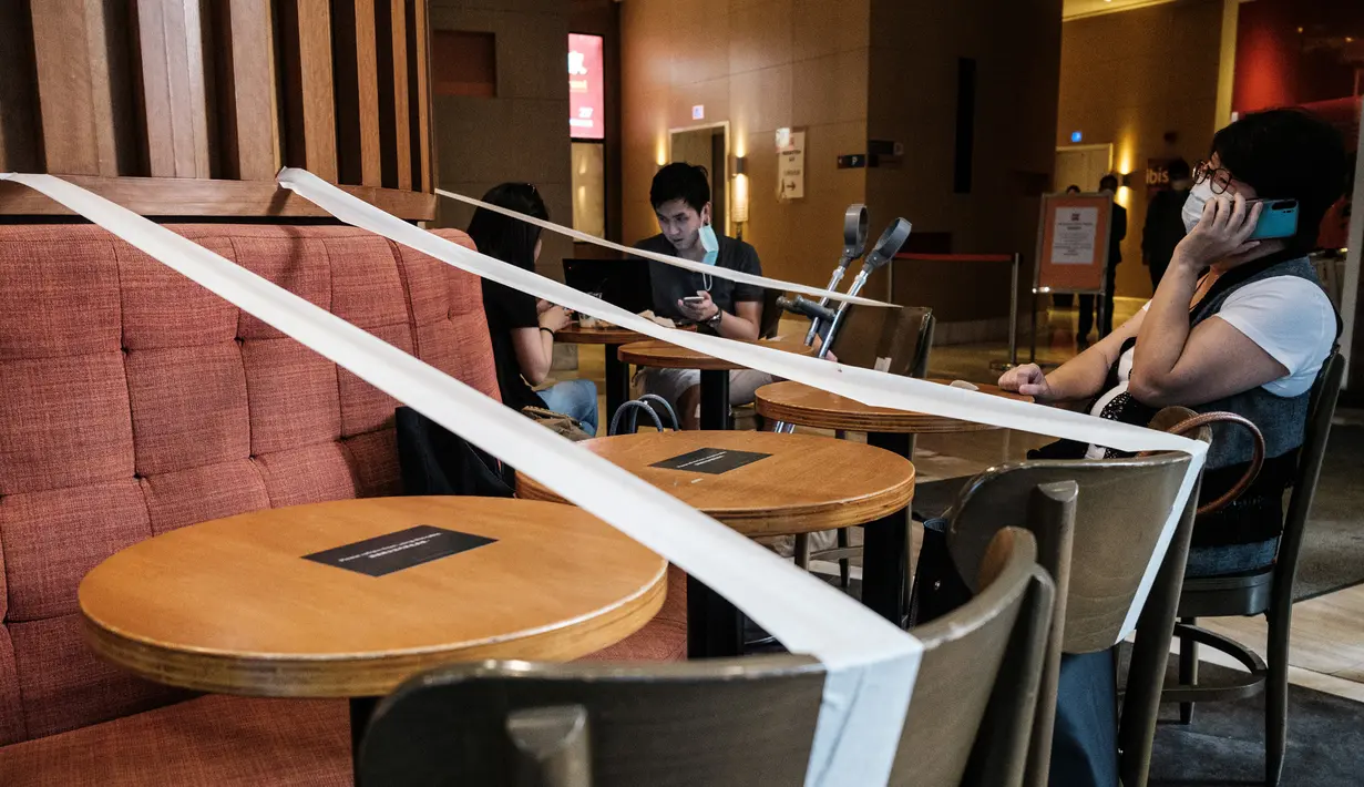 Pelanggan duduk di sebuah kafe, yang memiliki selotip di setiap meja untuk pembatasan jarak sosial, di Hong Kong (21/4/2020). Kepala eksekutif Carrie Lam mengatakan langkah-langkah jarak sosial dan beberapa pembatasan bisnis akan berlanjut selama dua minggu hingga setidaknya 7 Mei. (AFP/Anthony Wall