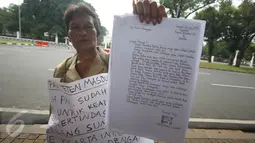 Nelly Hutabarat, guru asal Deli Serdang, menunjukkan surat untuk Presiden Jokowi di depan Istana Negara, Jakarta, Rabu (13/7). Nelly menuntut keadilan atas penutupan SDN 10-61-59 dan pembongkaran rumah dinasnya 2011 silam. (Liputan6.com/Immanuel Antonius)