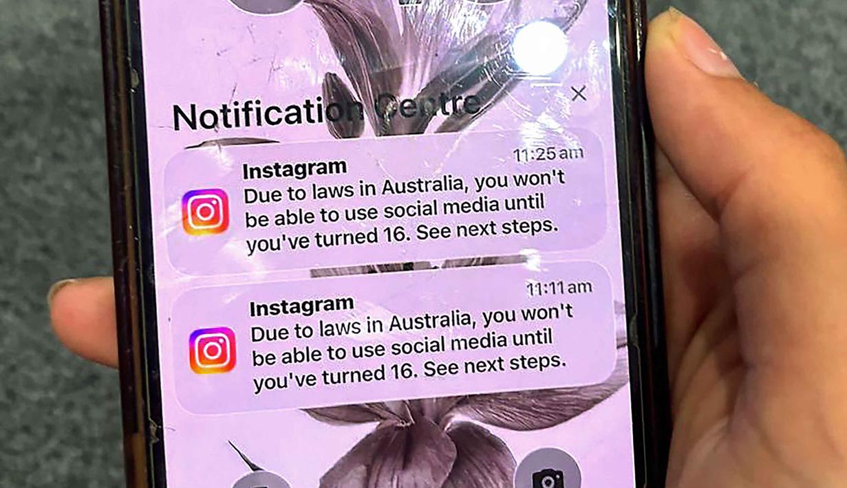 Seorang remaja memegang ponsel yang menampilkan pesan dari platform media sosial Instagram setelah akunnya dikunci untuk verifikasi usia di Sydney, Australia pada Selasa 9 Desember 2025. Australia akan melarang anak di bawah 16 tahun menggunakan media sosial mulai Rabu 10 Desember 2025. (Foto oleh AFP)